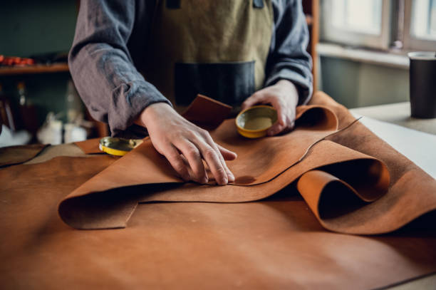 The initial stage of production of leather shoes, a young guy lays out the leather on the table for further use stock photo