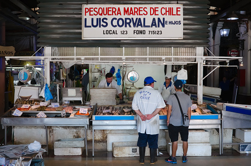 Santiago de Chile, Chile - February, 2020: Seafood vendor with raw fish on fish market on Central Market (Mercado Central) if Santiago de Chile. Family business store.