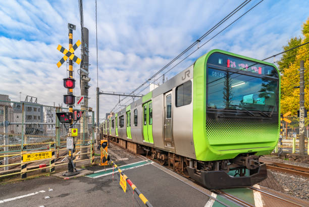 pociąg linii yamanote przejeżdżający przed barierami przejazdu kolejowego nakazato ii w komagome. - driverless train zdjęcia i obrazy z banku zdjęć
