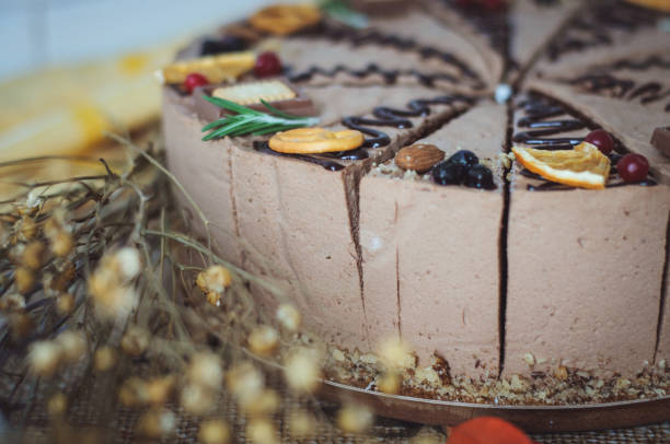 istock chocolate cake decorated with chocolate, cookies and dried orange. A round mousse cake, cut into pieces, is on a brown kraft tablecloth. 1291441908