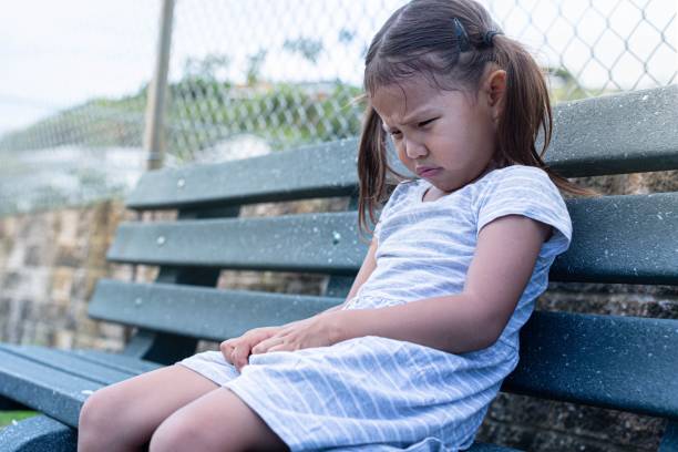 istock Sad little girl sitting alone at school. Depression. 1291443712