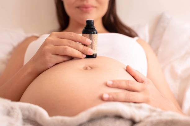 une femme enceinte utilisant l’huile essentielle pour la santé et la beauté de peau. remède de relaxation. - huiles essentielles femmes enceinte photos et images de collection