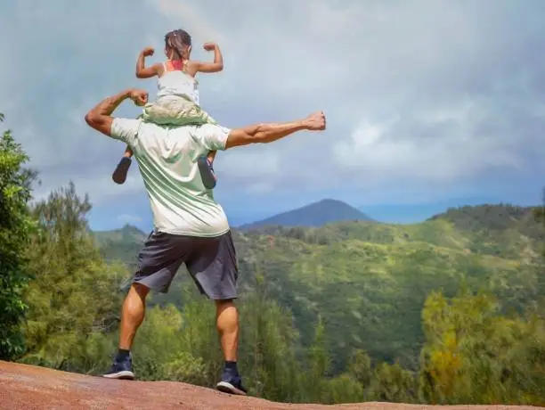 Photo of Active people hiking. Father and kid standing on top of a mountain.