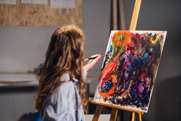 istock Young girl creative artist at work in a workshop. With passion draws a picture immersed in work 1291453100