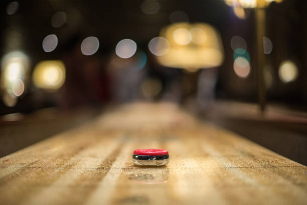 istock Red puck approaching the 3 point zone of a shuffleboard table.. 1291456338