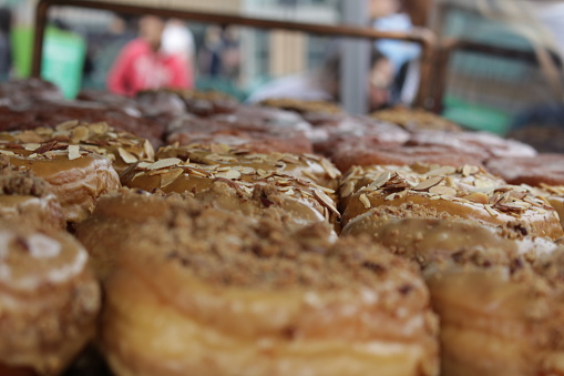 Dozens of fresh donuts on display in the cabinet of an outdoor cafe.