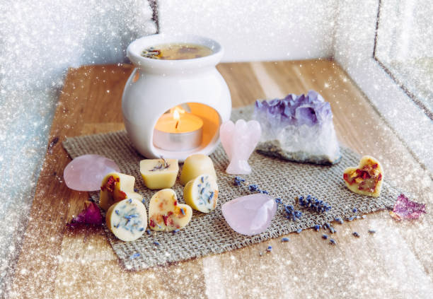 istock Homemade mini wax melts in aromatherapy lamp diffuser at home interior with rose quartz crystal hearts and angel for decoration on wooden window sill on winter. Seasonal spiritual zen concept. 1291458720