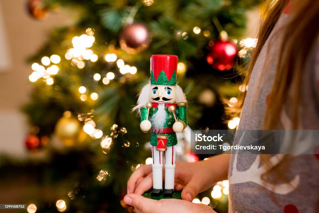 Close-up of child girl holding wooden nutcracker toy in hands. Christmas decoration symbol Close-up of child girl holding wooden nutcracker toy in hands. Christmas decoration symbol. Nutcracker Stock Photo