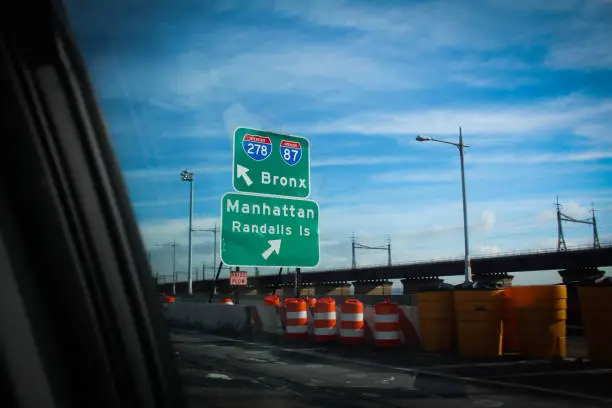 Signs for The Bronx and Manhattan. Seen from the interior of a passing car.