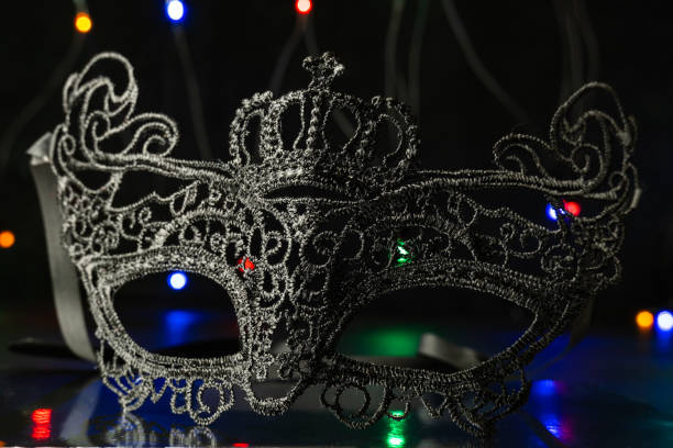 istock Black festive carnival mask on a black background with multi-colored garlands. 1291460412