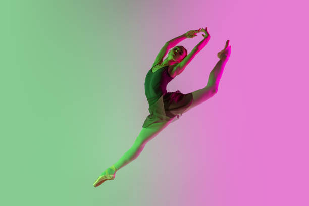 若くて優雅なバレエダンサーは、ネオンライトのグラデーションピンクグリーンのスタジオの背景に隔離されています。動いているアート - dancer jumping ballet dancer ballet ストックフォトと画像