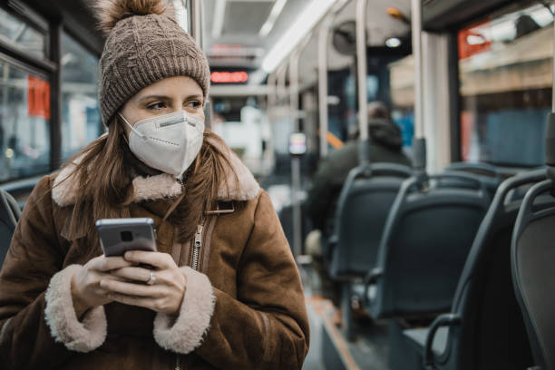istock A woman with a face mask is using mobile phone on public transportation 1291473782