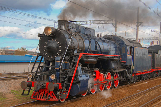 Steam locomotive in clouds of smoke rides on the railway stock photo