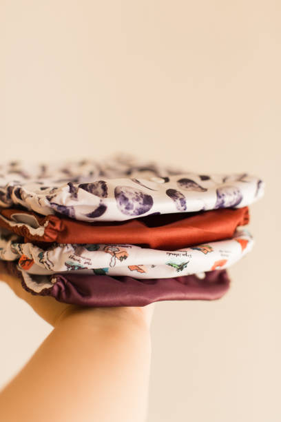 istock A Woman Holding a Slim Stack of Modern Neutral-Colored Reusable Cloth Diapers with a Neutral Background in Bright Natural Light 1291479930