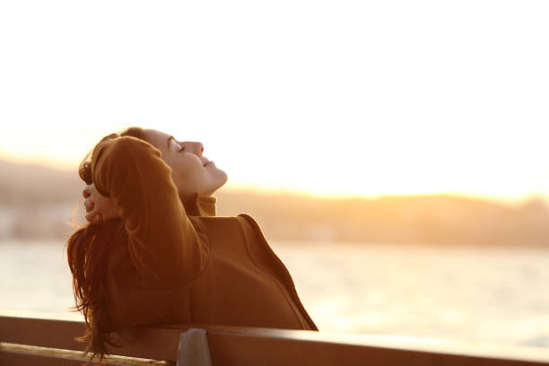 frau entspannt sich im winter am strand auf einer bank - women winter autumn nature stock-fotos und bilder