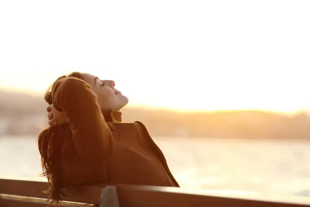 Photo of Woman relaxing on a bench in winter on the beach