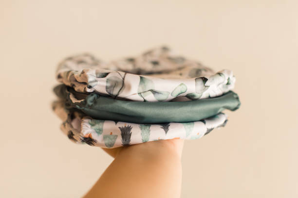 istock A Woman Holding a Slim Stack of Modern Green-Colored Reusable Cloth Diapers with a Neutral Background in Bright Natural Light 1291480075