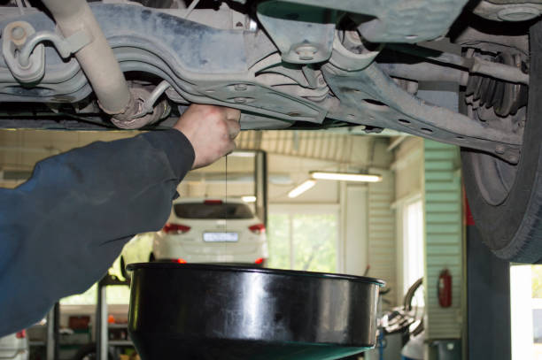 The mechanic unscrews the plug of the engine pan