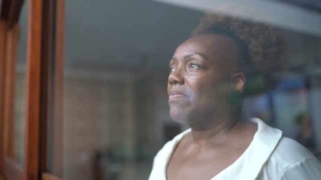 Senior woman looking through the window