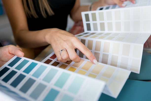 벽 페인트 샘플을 선택하는 두 여성의 클로즈업. 인테리어 디자이너가 컬러 스와츠를 보고 있는 클라이언트를 컨설팅합니다. 하우스 리노베이션 컨셉 - 색상 묘사 뉴스 사진 이미지