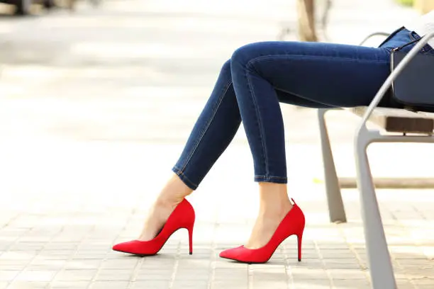 Woman legs with jeans and high heels in a bench