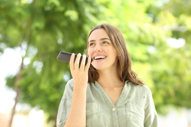 donna felice che registra un messaggio audio al telefono in un parco - human settlement audio foto e immagini stock