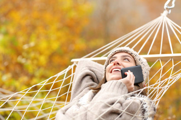 istock Happy woman on hammock talking on phone in autumn 1291491328