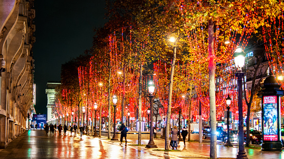 Christmas decorations with red garlands in the tree on the Champs Elysées avenue, at Christmas approaches. Paris in France. December 14, 2020.