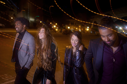 Group of multi-ethnic friends on streets walking from party at night