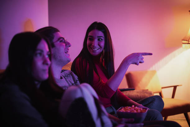 istock Cheerful friends eating snacks while watching a movie at home 1291498531