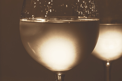 Two wineglasses with cold white wine backlit with sunlight, close up