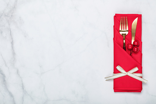 Cutlery tablecloth and berries on white.  Holiday Christmas food background concept. Christmas table setting with a set of cutlery knife and fork on a red napkin with xmas decorations. White marble background. Christmas menu concept.