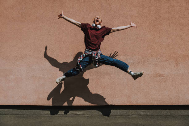 istock Joyful excited hipster man jumping high outdoor 1291504604