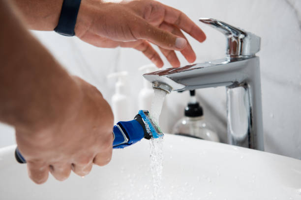 istock Young man washing razor under tap water 1291504608