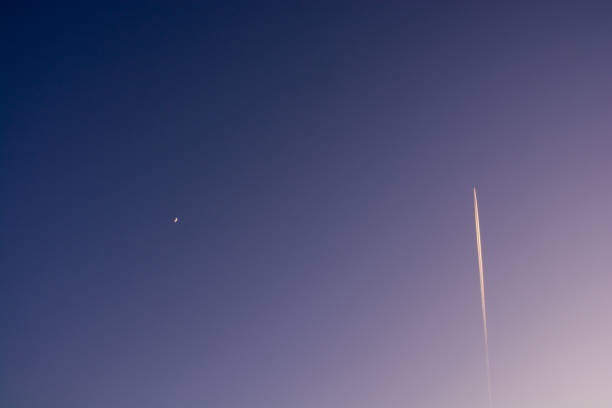 Crescent moon and contrail in the winter evening sky Crescent moon and contrail in the winter evening sky contrail moon on a night sky stock pictures, royalty-free photos & images
