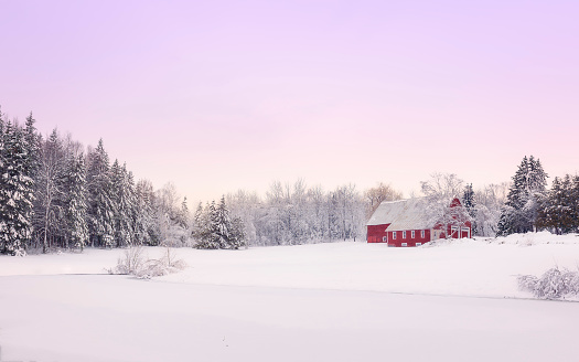 A beautiful red barn sits in a snowy landscape after a good Northern Maine snow storm laid a blanket of snow over the landscape.