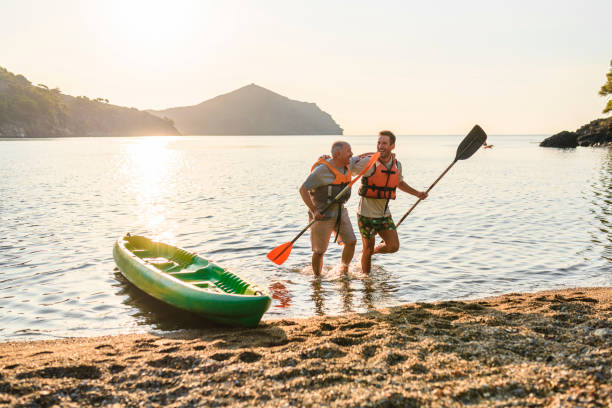 kayakisti maschi che camminano sulla spiaggia con pagaie dopo l'esercizio - 2417 foto e immagini stock