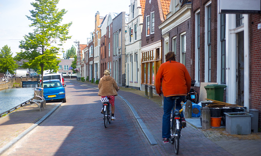 Two People Riding Bikes in Dutch Town Near Canal. Shot in Sneek, Friesland, Netherlands.