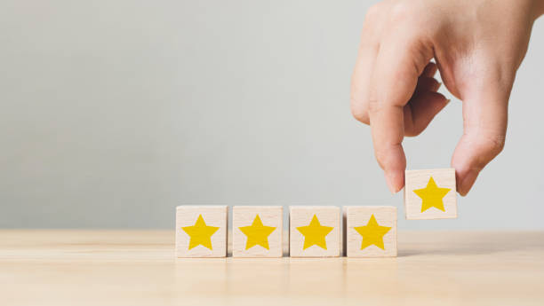 istock Hand putting wooden cube with five star shape on wood table with copy space. The best excellent business services rating customer experience concept 1291517556