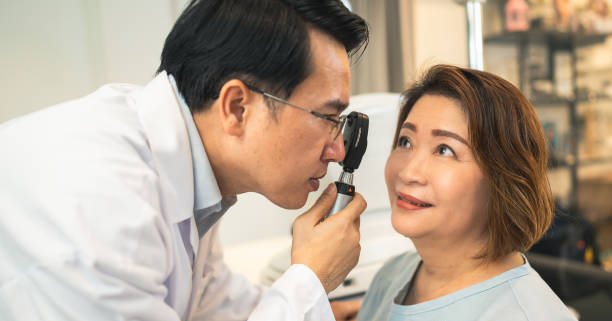 optometrist checking eyes condition of client before check eyesight in optical store optometrist checking eyes condition of client before check eyesight in optical store eye exam stock pictures, royalty-free photos & images