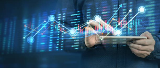 istock Hand holding smartphone device and touching screen. businessman trader looking on with graphs analysis candle 1291519359