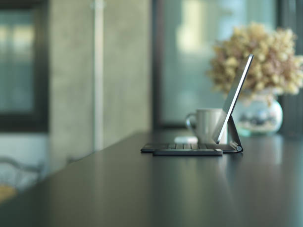 Side view of portable workspace with tablet, cup and flower vase on black table