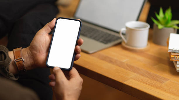 istock Male hands using smartphone while sitting at workplace with laptop and supplies 1291521057