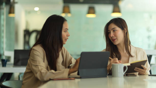 istock Two female office workers talking to each other while working in meeting room 1291521235