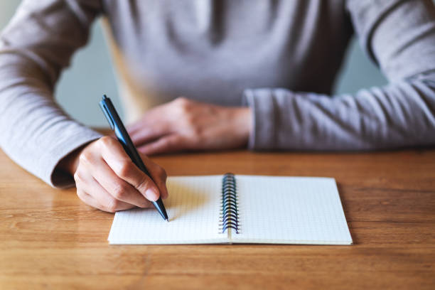 istock a woman writing on a blank notebook on the table 1291526007