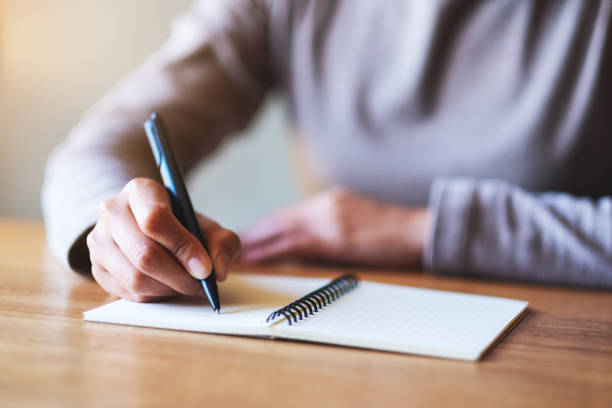 istock a woman writing on a blank notebook on the table 1291526051