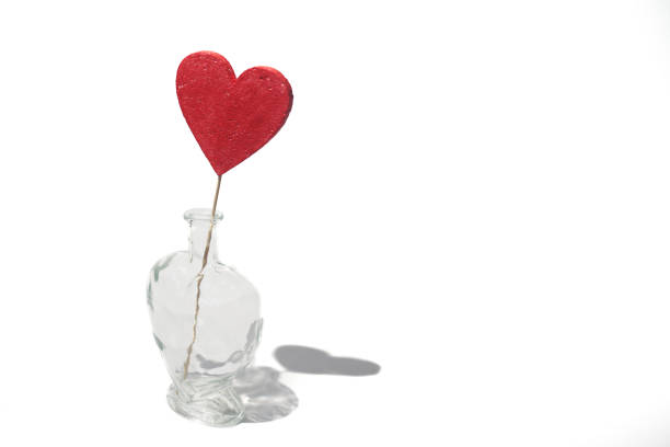 Concept red heart in a transparent decanter with a hard shadow on the white background. Trending for Valentine's day