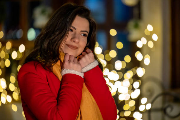 Beautiful woman on the street in the night. She is trying to cover her neck with scarf and get worm. She fills nice and satisfied.