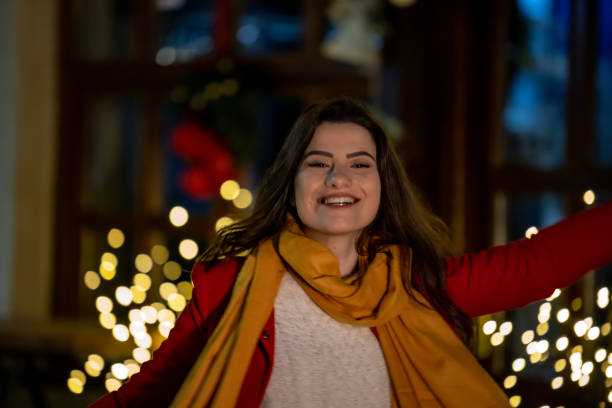 Lovely young woman on the street surrounded with Christmas decoration is smiling an enjoy the holiday.