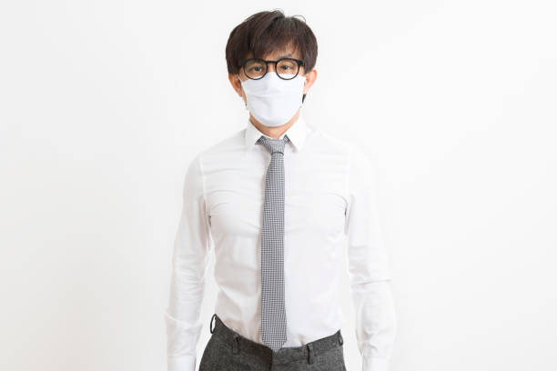 istock Handsome Asian man in a white shirt with face mask on white wall background. 1291532008